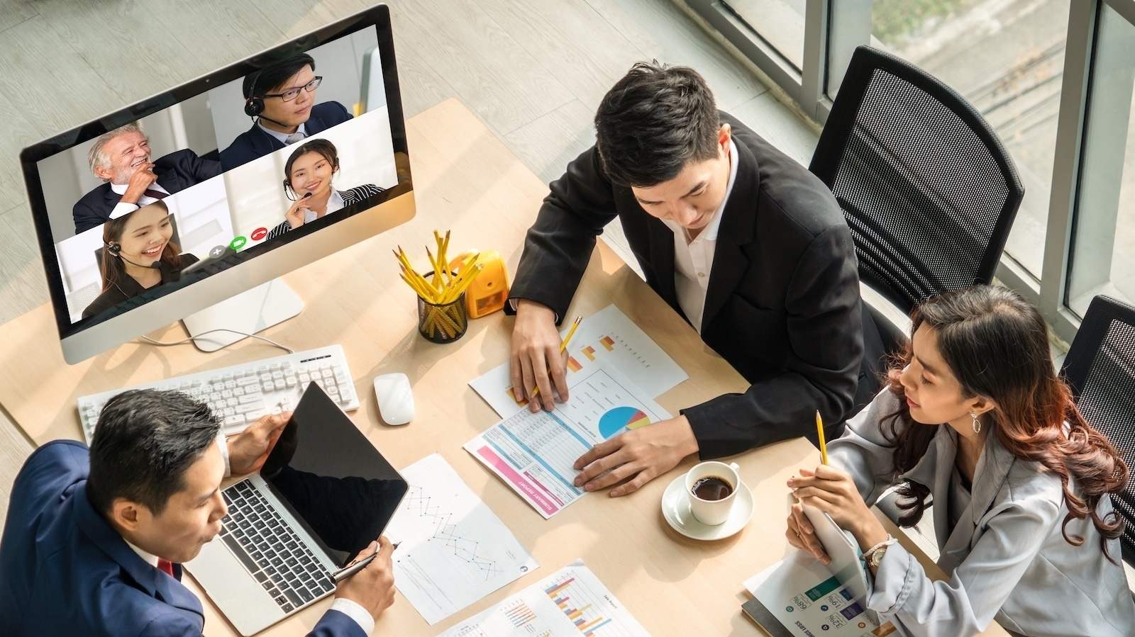 team in office meeting with coworkers on video call